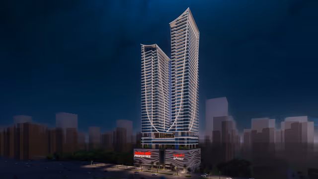 Elitz by Danube – twin curved-glass towers at night above the Danube podium in JVC
